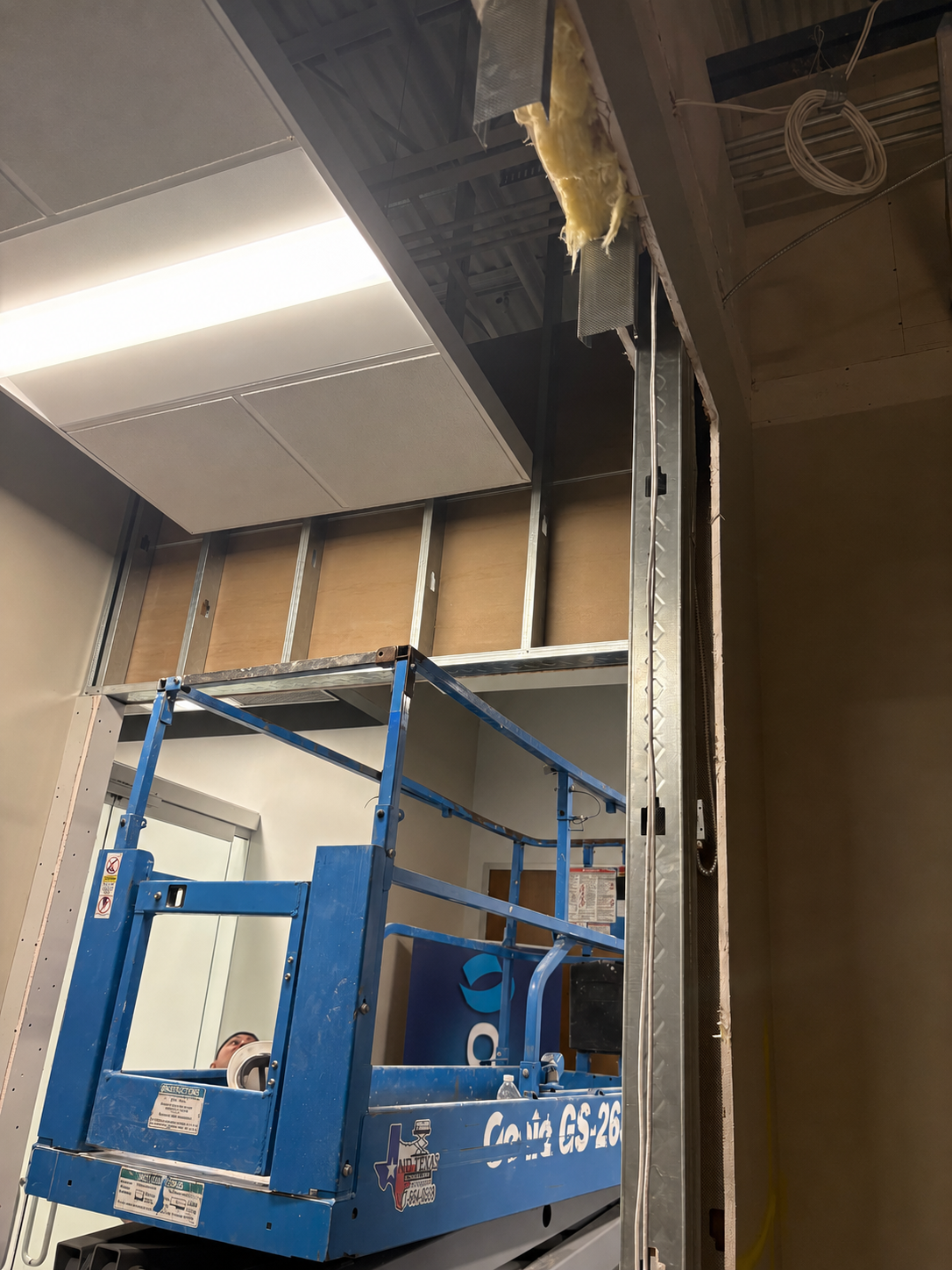 Overhead ductwork and ceiling grid installation above a construction area